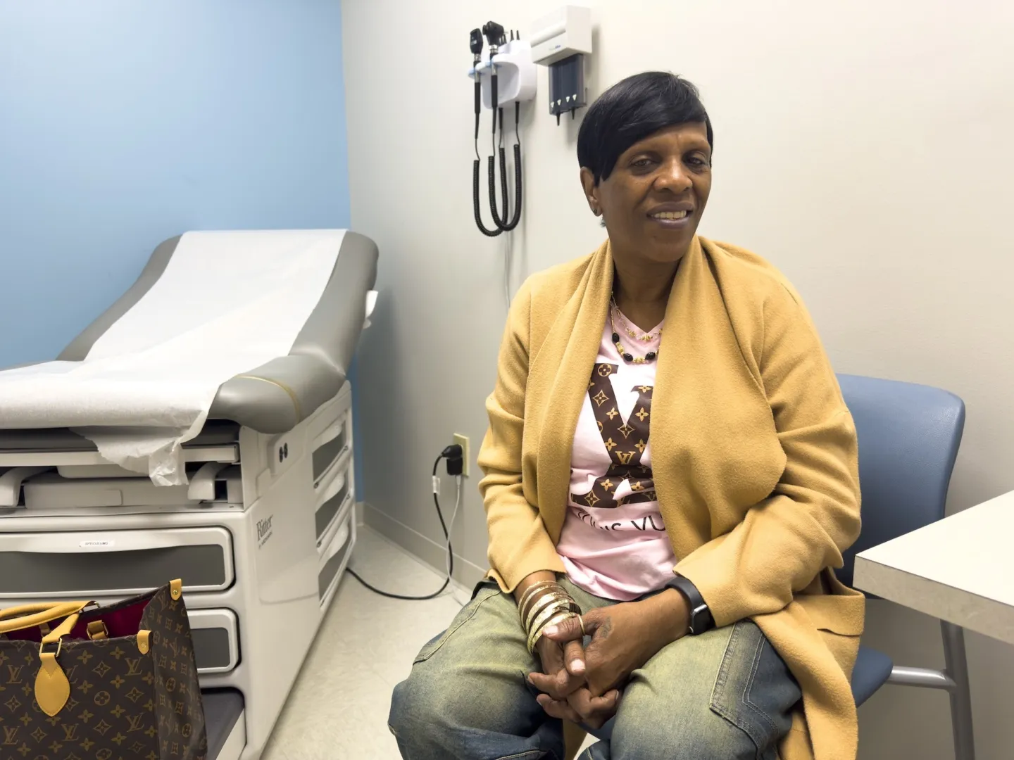 older woman in yellow sweater sitting inside medical room
