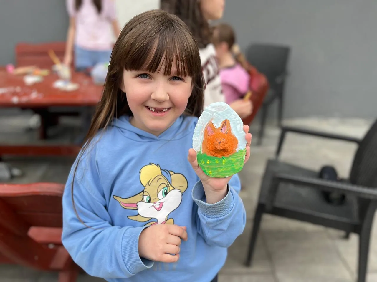 Young girl shows painting to camera while smiling