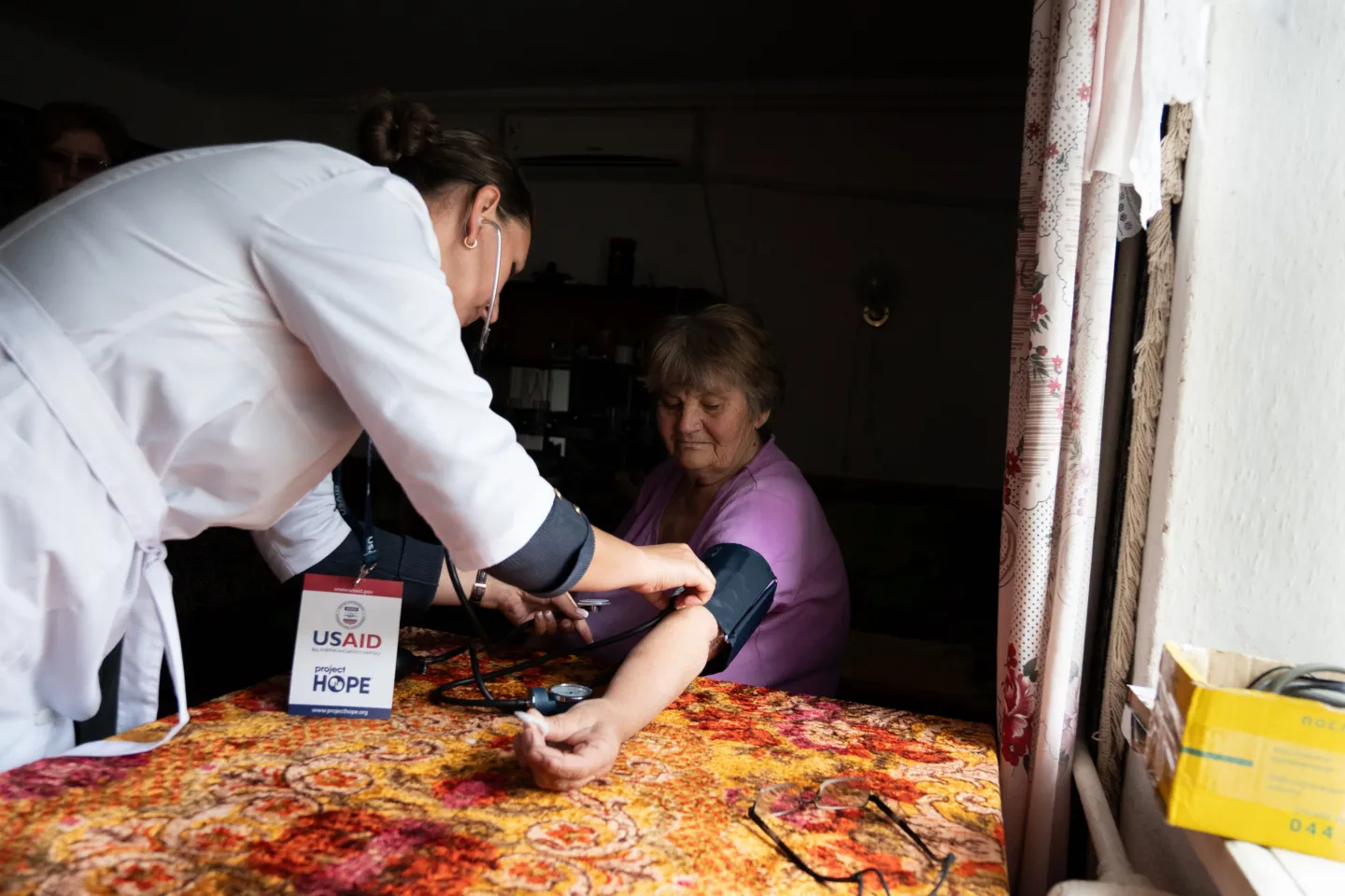 woman gets blood pressure taken in home by medical staff in Ukraine